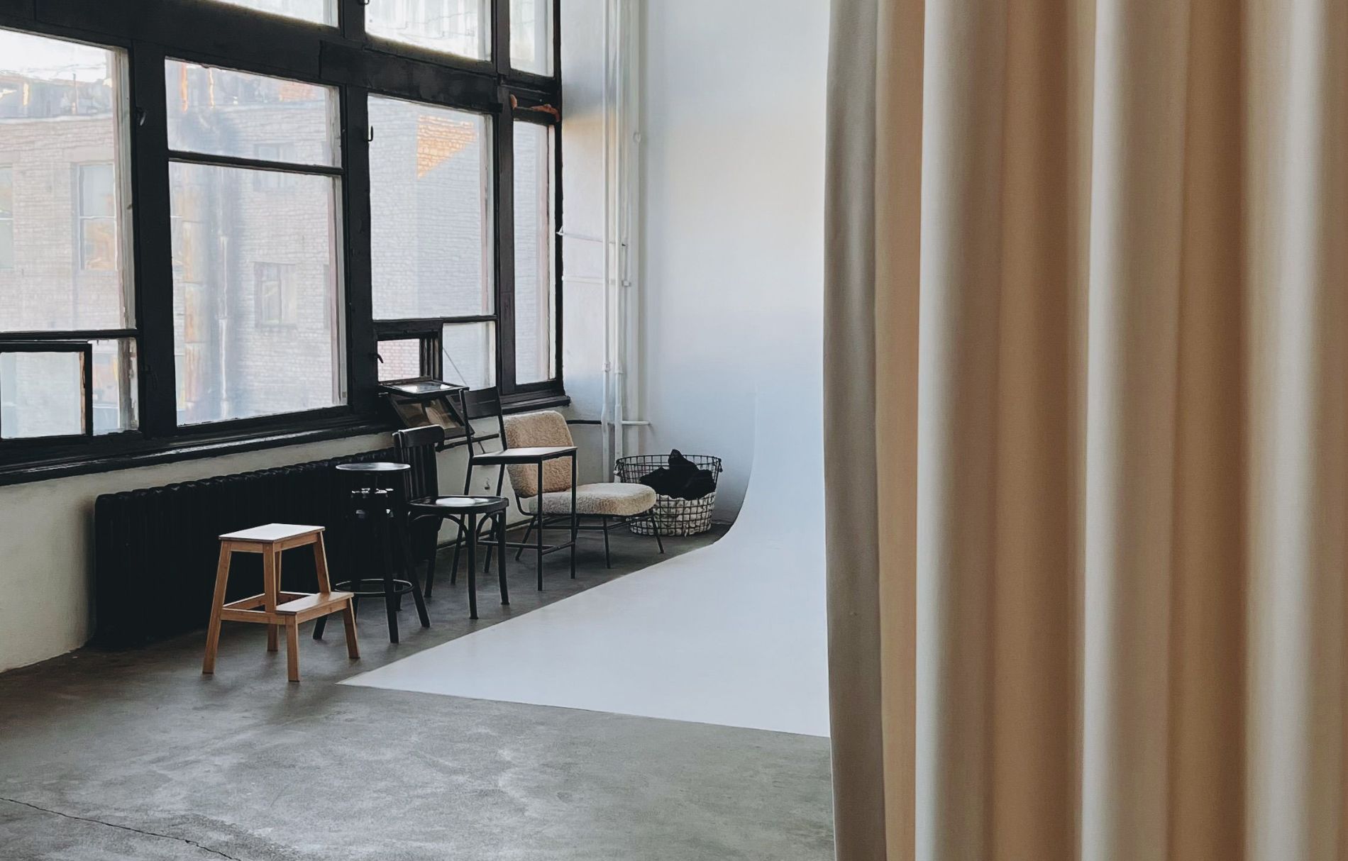 Light-filled studio with tall windows, concrete floor and a linen curtain